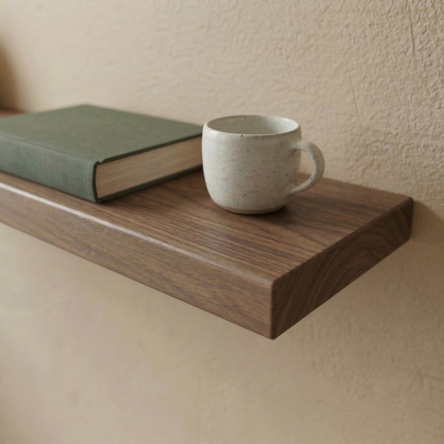 Detailaufnahme eines schwebenden Wandregals aus massivem Nussbaum mit Buch und Tasse auf der Oberfläche