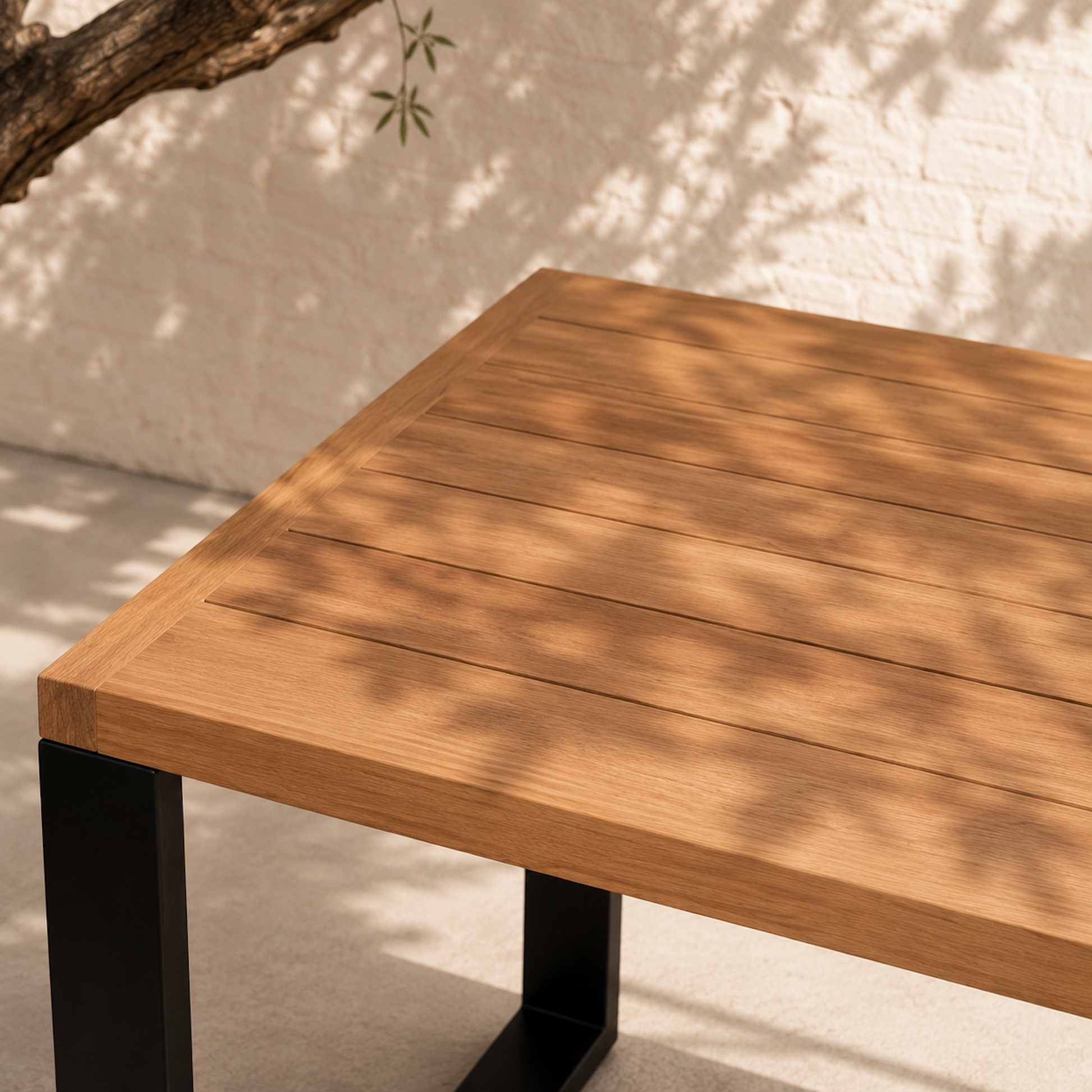 Detailaufnahme des Gartentischs Urban aus massiver Eiche mit schwarzem Stahlgestell und hochwertiger Holzmaserung. Moderner Outdoor-Esstisch aus Eichenholz im warmen Sonnenlicht auf mediterraner Terrasse.