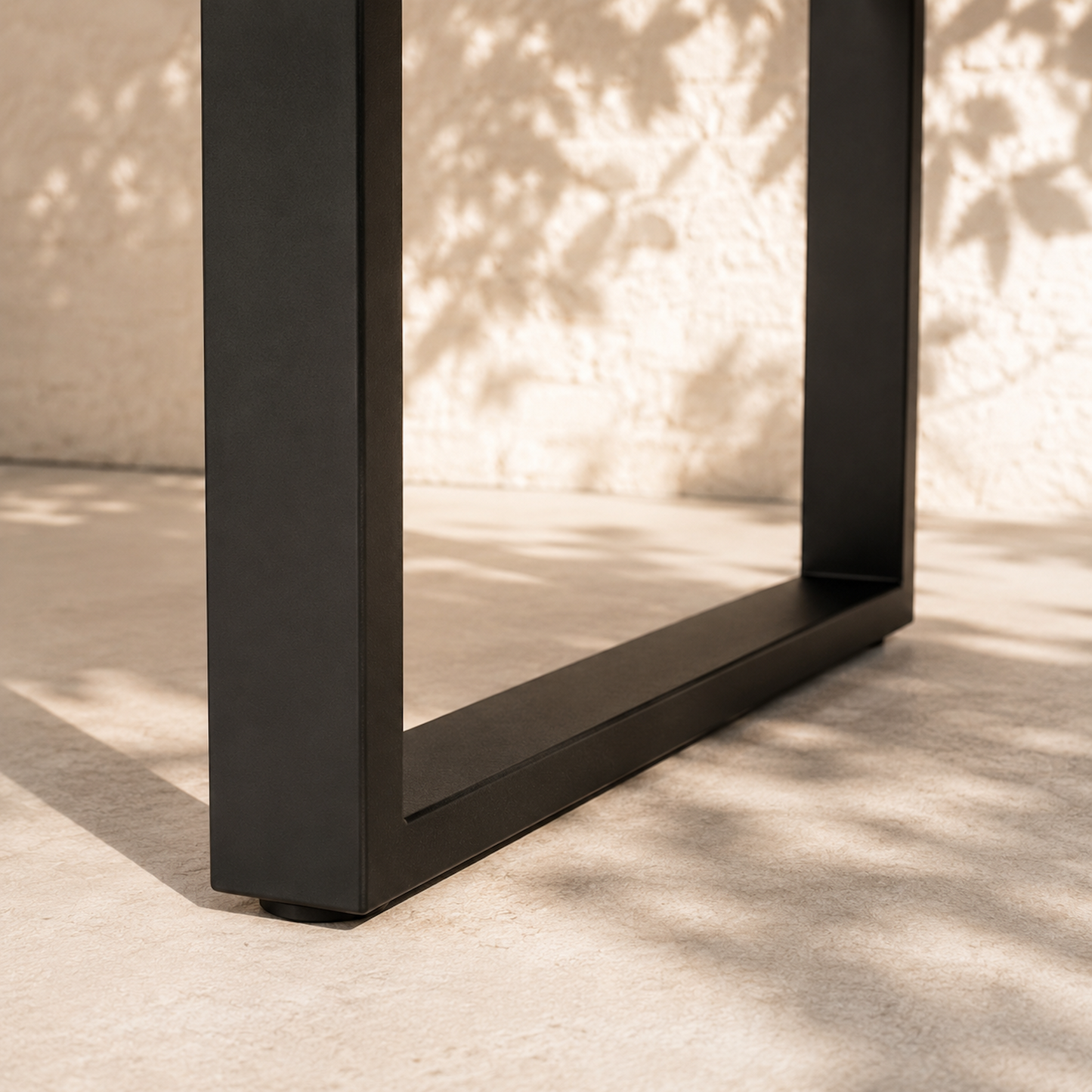 Detailaufnahme der schwarzen Stahlkufe des Gartentischs Urban aus massiver Eiche. Pulverbeschichtetes Metallgestell eines modernen Outdoor-Esstischs im minimalistischen Design.