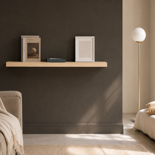 Schwebendes Wandregal aus Ahorn Massivholz an dunkler Wand mit Büchern und Bilderrahmen in modernem Wohnraum mit minimalistischer Einrichtung und warmem Tageslicht