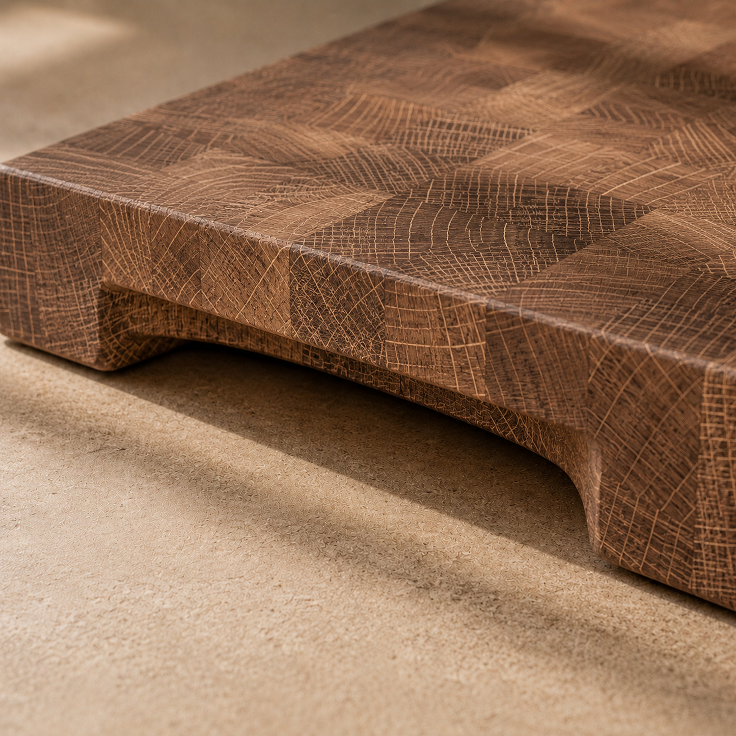 Detailaufnahme der integrierten Griffmulde eines massiven Stirnholz-Schneidebretts aus Eiche mit markanter Endgrain-Struktur und warmer Holzfarbe.