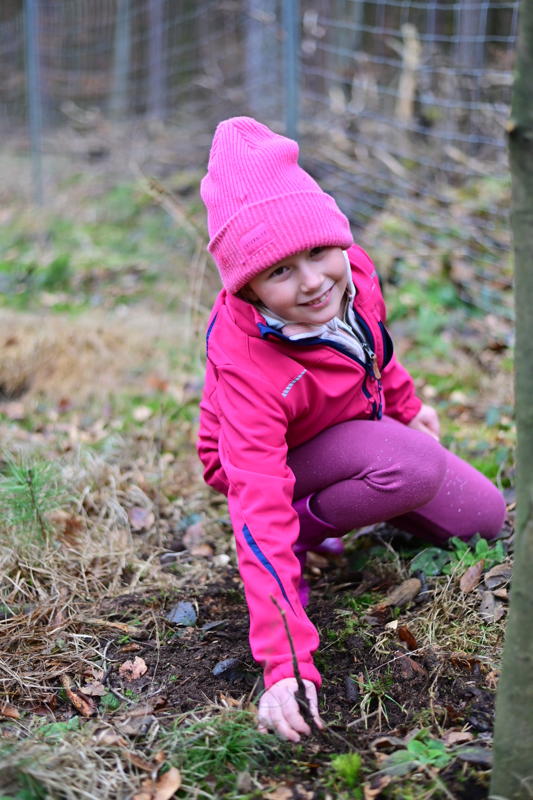 Kind pflanzt einen jungen Baum im Wald bei einer Aufforstungsaktion mit Planet Tree
