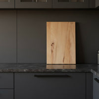 Schneidebrett aus massiver Buche, stehend auf dunkler Küchenarbeitsplatte vor moderner Küche