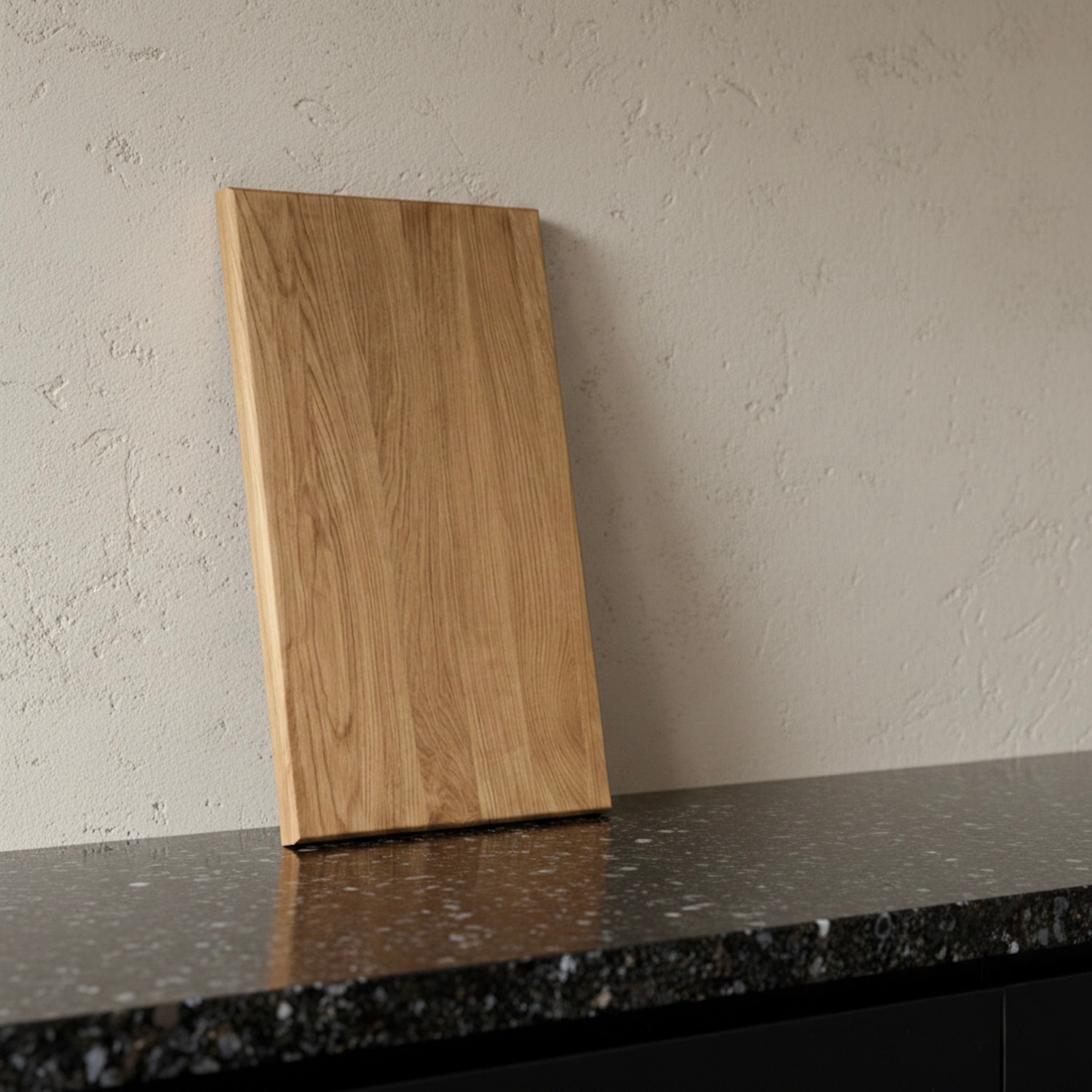 Schneidebrett aus massiver Eiche, stehend auf dunkler Arbeitsplatte vor heller Wand
