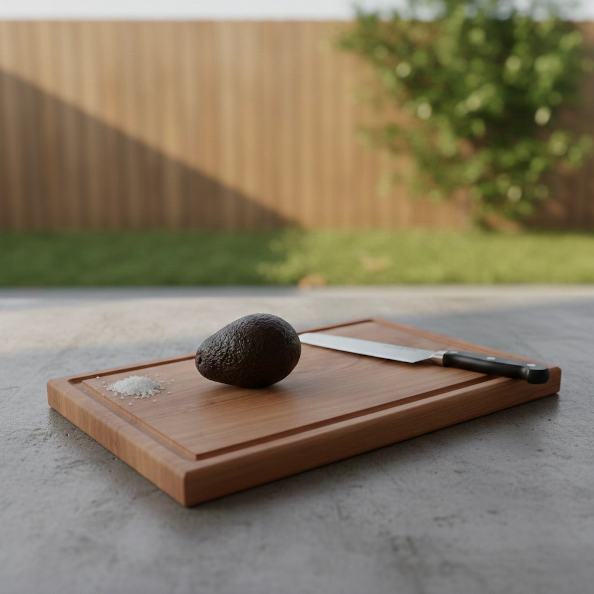 Schneidebrett aus massivem Kirschbaum mit Saftrille, liegend mit Avocado, Salz und Messer