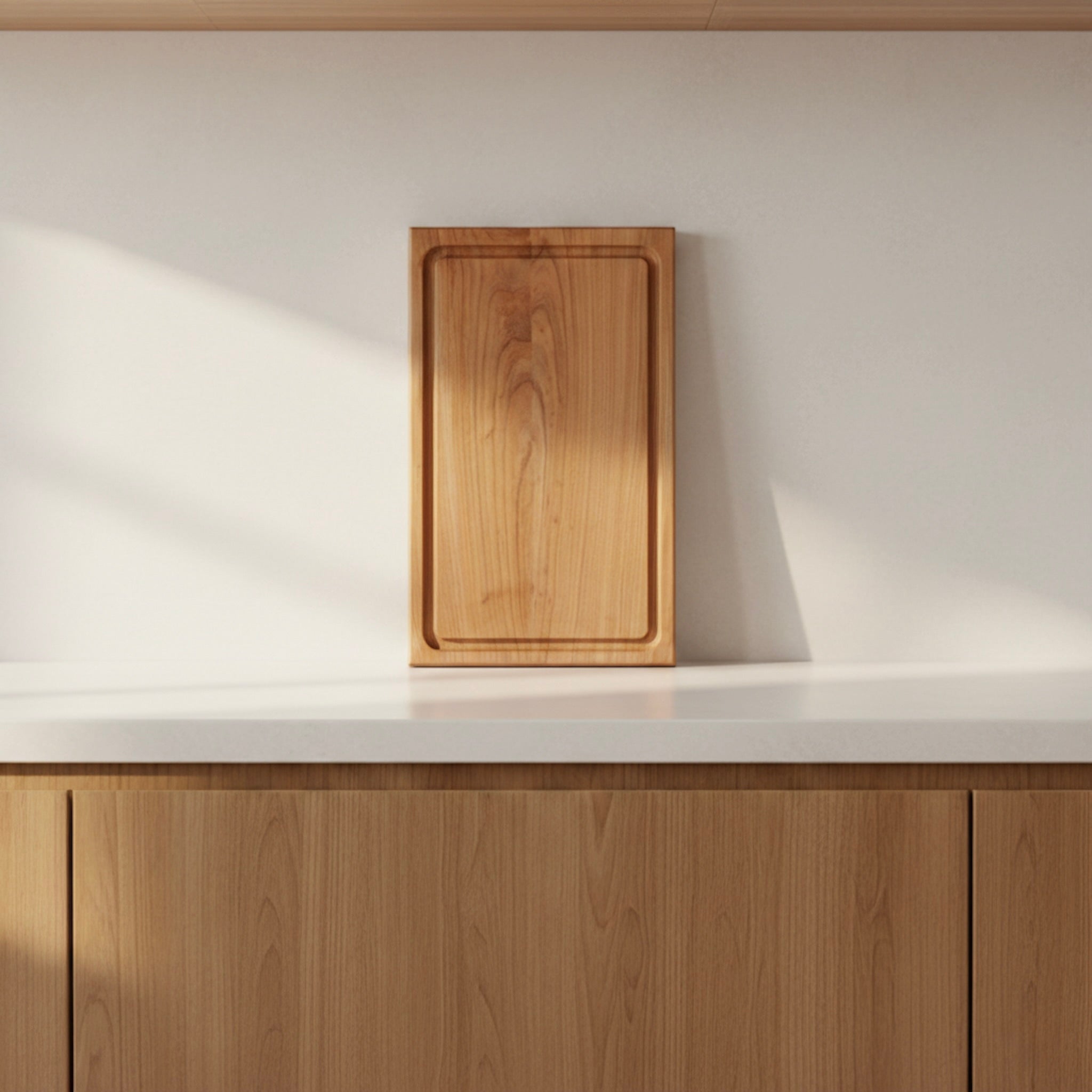 Schneidebrett aus massivem Kirschbaum mit Saftrille, stehend auf heller Küchenarbeitsfläche