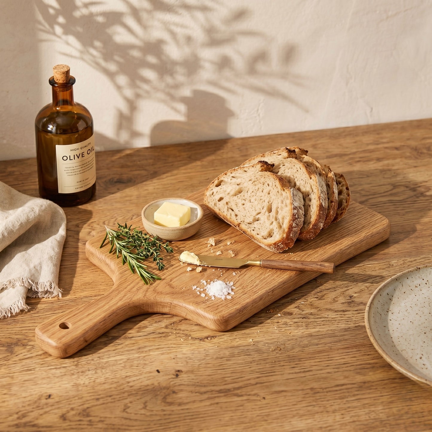 Servierbrett aus massiver Eiche mit frischem Sauerteigbrot, Butter und Kräutern in warmer, rustikaler Küchenatmosphäre mit natürlichem Licht.