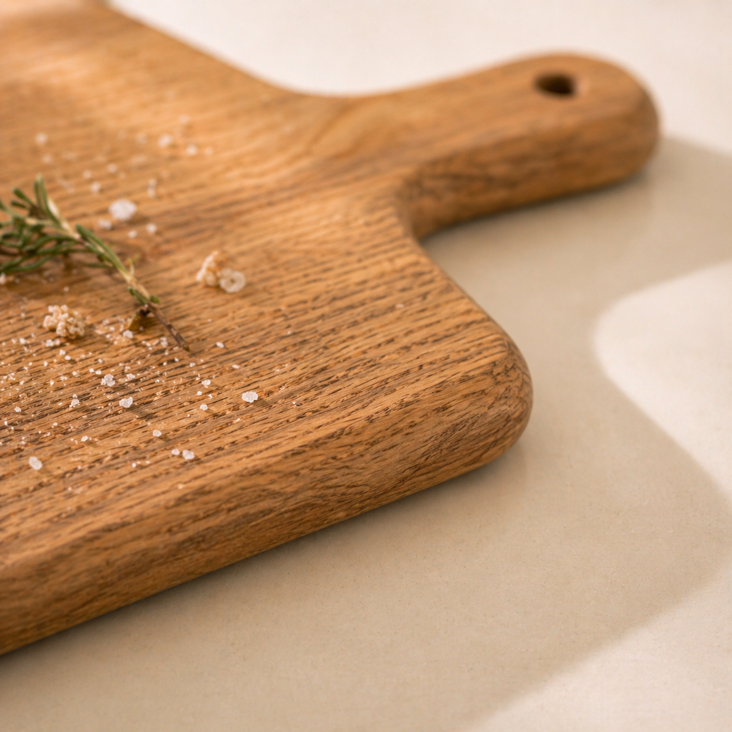 Detailaufnahme eines handgefertigten Servierbretts aus massiver Eiche mit abgerundeten Kanten, Griff und natürlicher Holzmaserung.