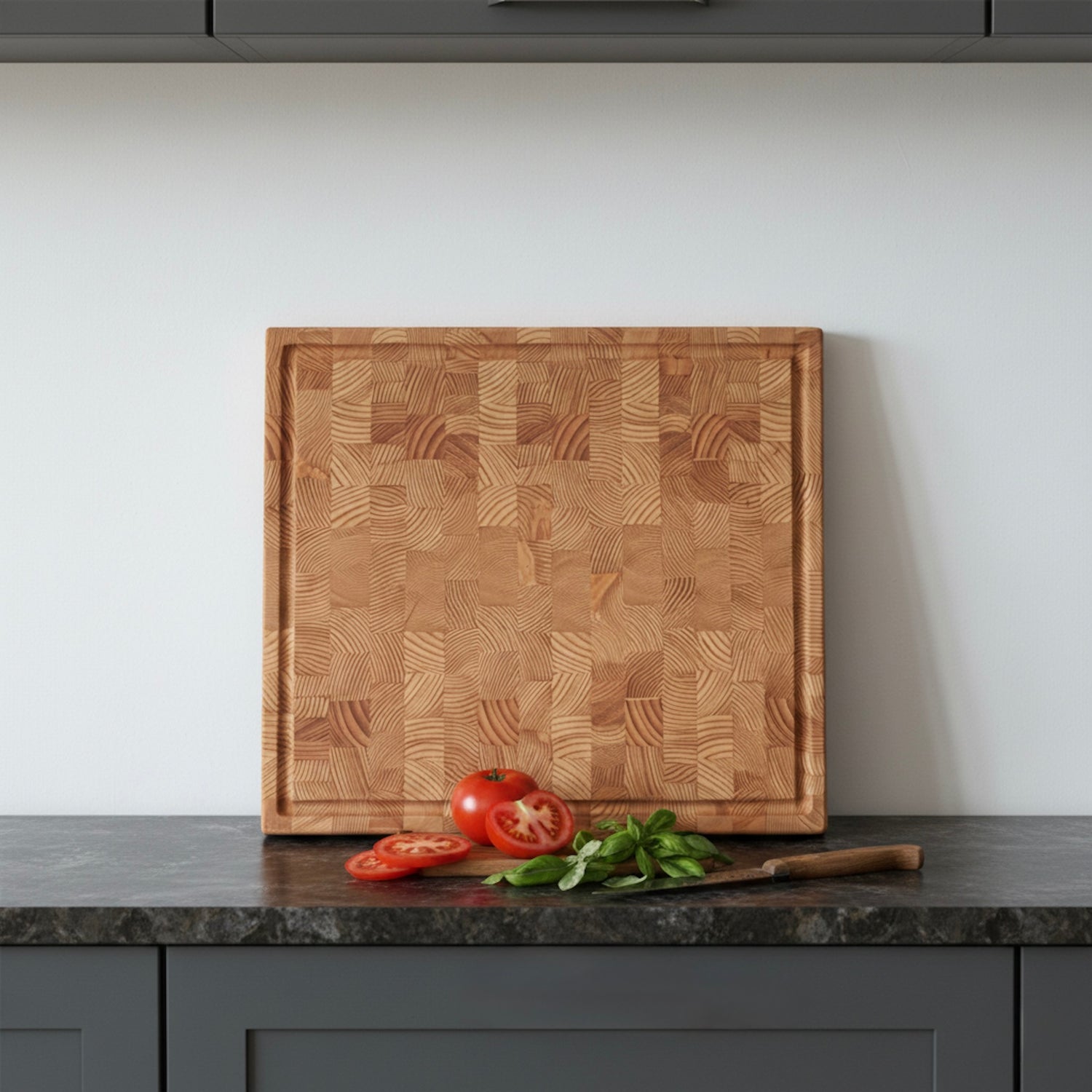 Stirnholz Schneidebrett aus Lärche mit Saftrille, Tomaten und Kräutern auf dunkler Arbeitsplatte in moderner Küche
