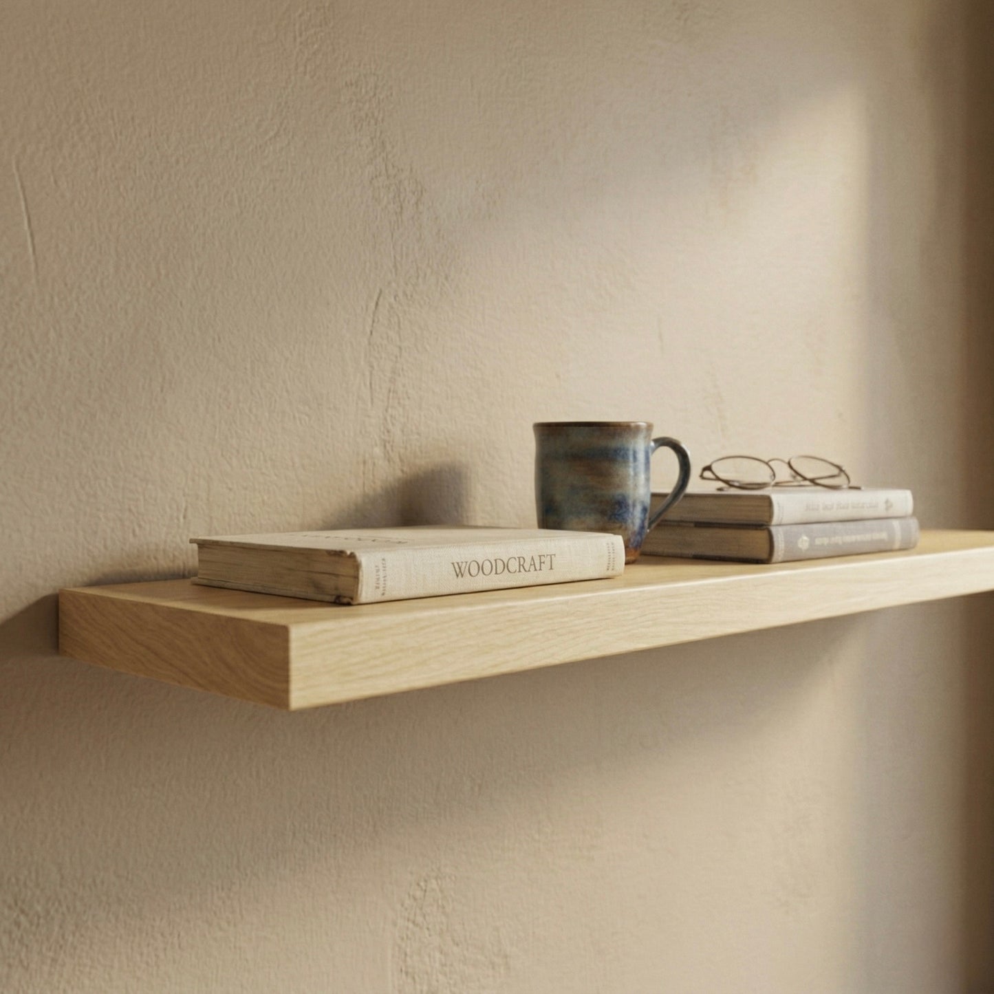 Detailaufnahme eines schwebenden Wandregals aus Birke furniert mit Büchern, Brille und Tasse in warmem Licht