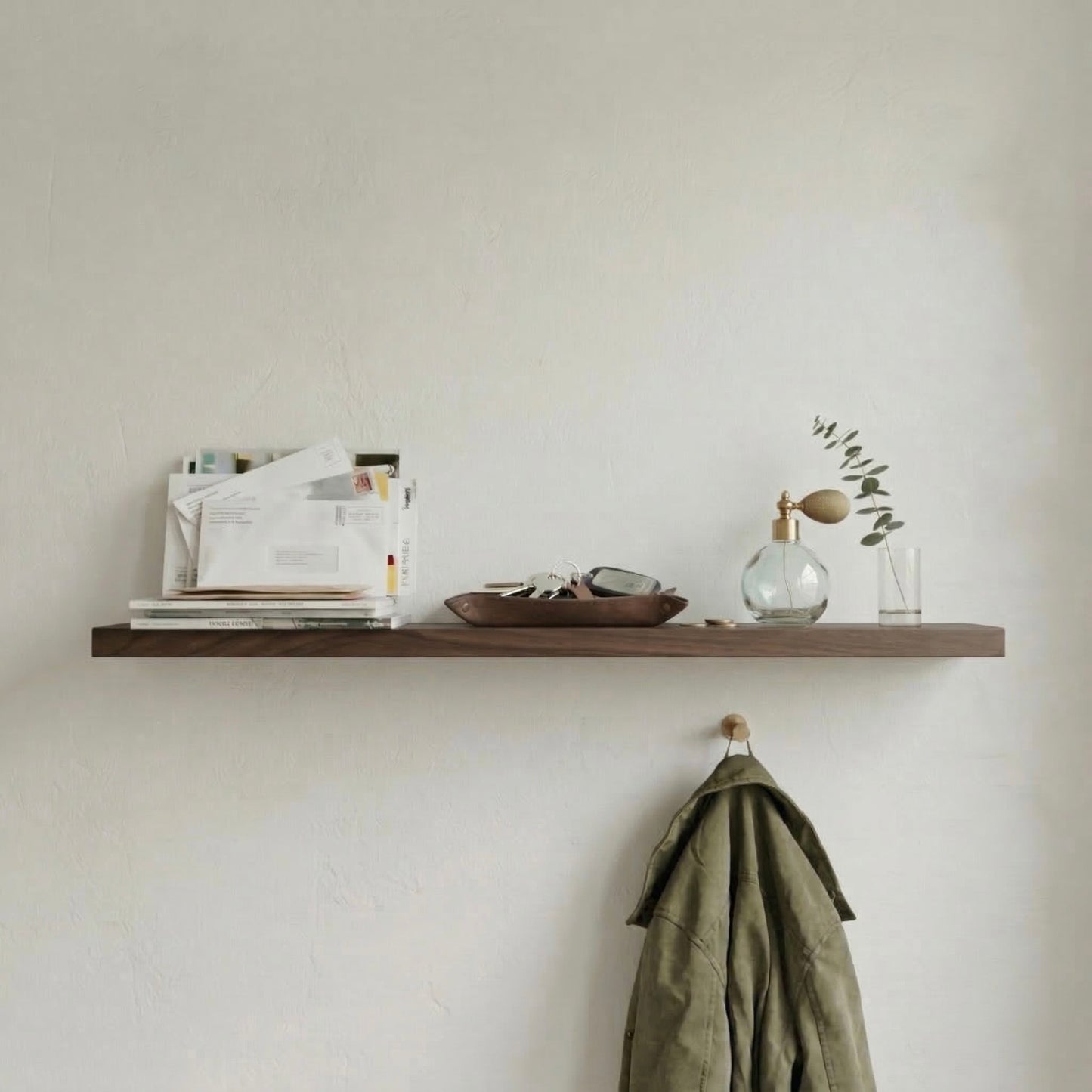 Schwebendes Wandregal aus Nussbaum furniert im Flur mit Post, Schlüsseln und Dekoelementen in ruhiger, minimalistischer Atmosphäre
