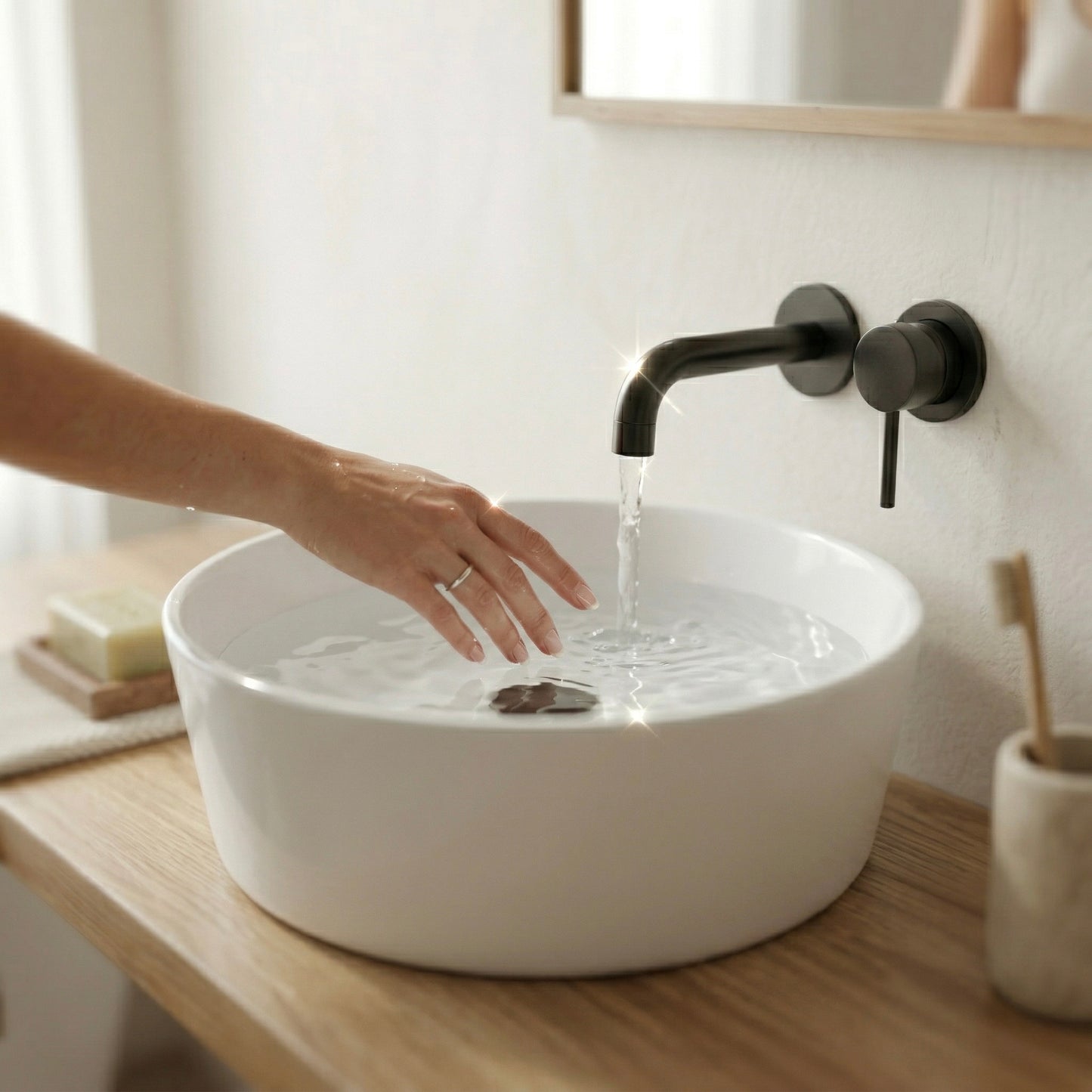 Detailaufnahme des Linea Loft Solo Waschtischs aus Eiche mit weiß glänzendem Aufsatzwaschbecken, schwarzer Wandarmatur und fließendem Wasser, Hand im Waschbecken
